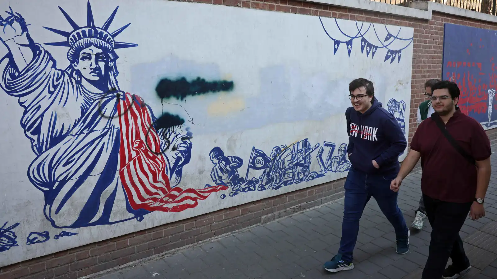 إيرانيون يمرون أمام جدارية مناهضة للولايات المتحدة في طهران