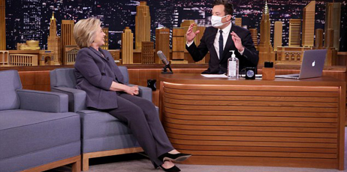 في أول ظهور بعد المرض..مذيع أمريكي يستقبل هيلاري كلينتون بكمامة ومطهّر (فيديو وصور)