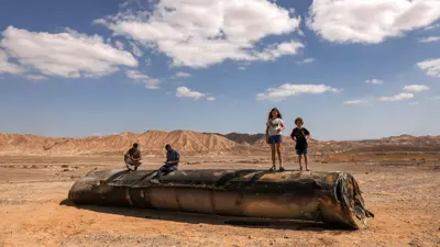 أشخاص يقفون فوق صاروخ إيراني سقط في جنوب إسرائيل