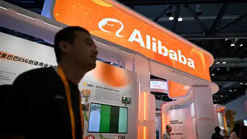 رجل يمر أمام كشك علي بابا في معرض الصين الدولي للتجارة 