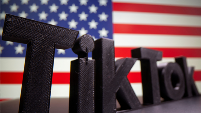 شعار تطبيق تيك توك وخلفه العلم الأمريكي