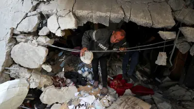 رجل ينظر من بين أنقاض منزله في غزة