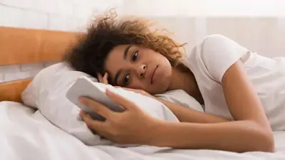 فتاة تبحث في هاتفها (تعبيرية)