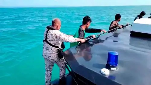 أحد أفراد القوات البحرية الماليزية يرشد الناجين من المهاجرين على متن قارب، قبالة ساحل لانكاوي، قدح، ماليزيا