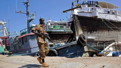جندي صومالي يمرّ بسفن أجنبية في ميناء بوصاصو