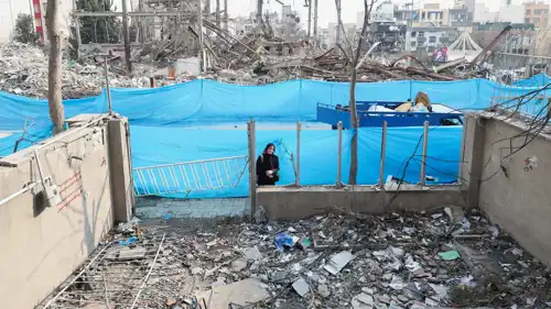 امرأة تنظر إلى منزلها جراء غارة جوية في طهران