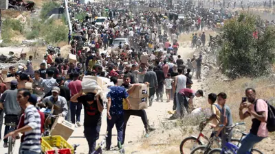 يحمل الناس صناديقَ إغاثة من مؤسسة غزة الإنسانية