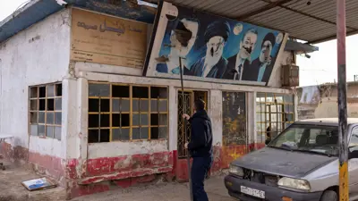 سوري يمزق صورا لرموز نظام الأسد وإيران