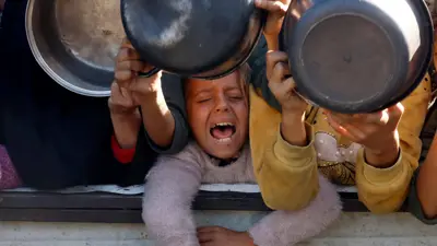 فلسطينيون يتجمعون لتلقي الطعام الذي تطبخه إحدى المطابخ الخيرية