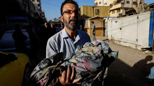 رجل يحمل جثمان طفل قتل في غزة رغم وقف إطلاق النار