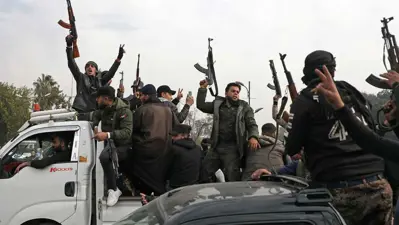 مقاتلون يلوحون بأسلحتهم احتفالا بسقوط نظام الأسد