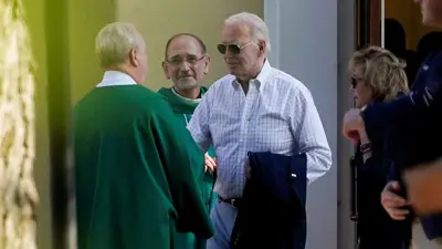 الرئيس الأمريكي جو بايدن يحيي كاهنًا أثناء مغادرته خارج سانت جوزيف في كنيسة برانديواين الرومانية الكاثوليكية في ويلمنجتون بولاية ديلاوير