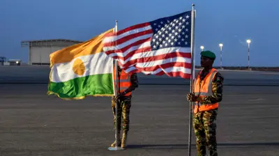 جنديان يحملان العلمين الأمريكي والنيجري في القاعدة الجوية 101 في نيامي