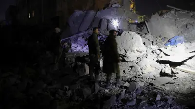 أفراد حوثيون يقفون في موقع ضربة أمريكية في صنعاء