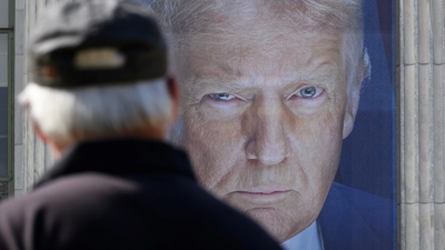 شخص يقف أمام صورة الرئيس الأمريكي دونالد ترامب