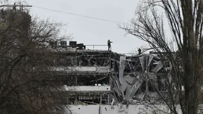 رجال إنقاذ أوكرانيون يعملون فوق مبنى مكاتب متعدد الطوابق متضرر إثر هجوم صاروخي روسي في كييف