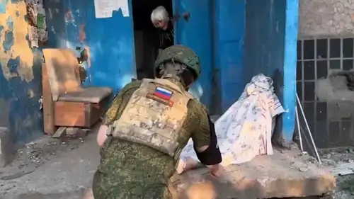 جندي روسي يعاين جثة أحد ضحايا الهجوم