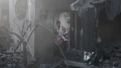 رجل يحمل فتاة فلسطينية مصابة في موقع غارات إسرائيلية على غزة