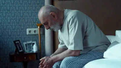 رجل كبير في السن يجلس على سريره 