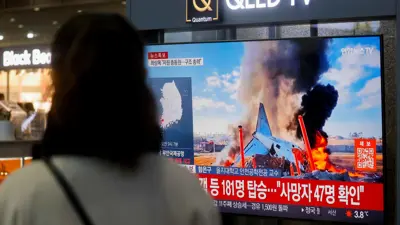 سيدة تشاهد حطام الطائرة عبر شاشة تلفزيونية