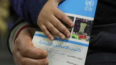 فلسطيني يحمل كتيبًا داخل مركز صحي للأونروا