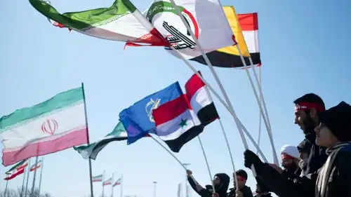 عراقيون يحملون رايات الفصائل الشيعية الموالية لإيران