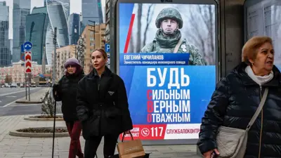 متسوقات بالمنطقة التجارية في موسكو أمام إعلان لجندي روسي