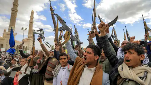 عناصر من مليشيا حزب الله يرفعون السلاح خلال مسيرة تندد بالتصعيد الأمريكي الإسرائيلي