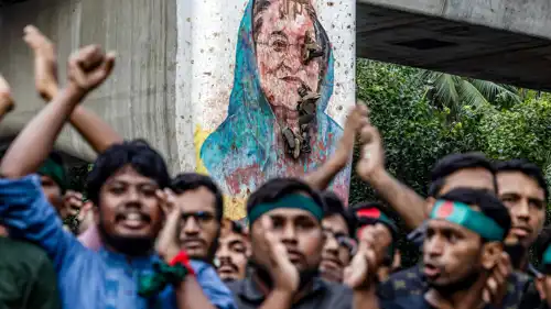 متظاهرو بنغلادش أمام لوحة للشيخة حسينة تم إتلافها