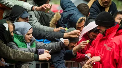 صورة أرشيفية لمهاجرون يعبرون حاجز نحو موظف في برلين