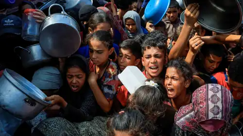 فلسطينيون ينتظرون استلام الطعام من مطبخ خيري في خان يونس، جنوب قطاع غزة