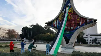 سوريون قرب أحد معالم دمشق الجديدة