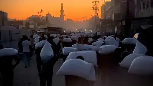 فلسطينيون يحملون أكياس الدقيق في غزة