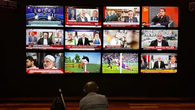 شخص يشاهد الأخبار على شاشات تلفزيونية متعددة، يعلن معظمها عن مقتل إسماعيل هنية