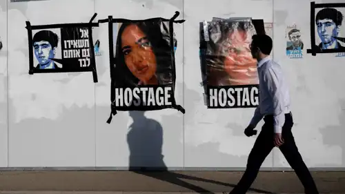 إسرائيلي يمر أمام صور للرهائن المحتجزين في غزة