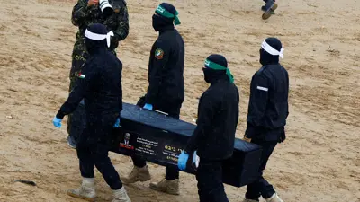 عناصر من حماس خلال تسليم جثث رهائن إسرايليين