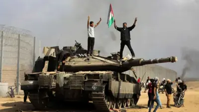 فلسطيني يرفع علم بلاده فوق دبابة إسرائيلية يوم 7 أكتوبر