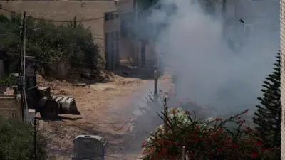 الدخان يتصاعد بجوار مركبة مدرعة خلال غارة إسرائيلية في جنين السبت