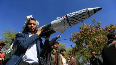 شخص يحمل مجسم صاروخ في فعالية للحوثيين