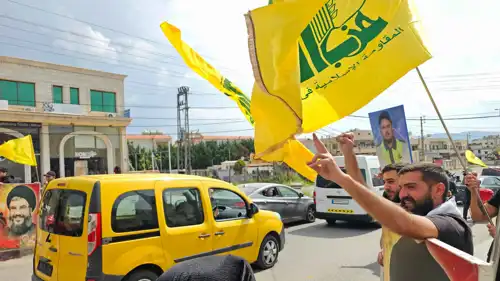 أشخاص يرفعون أعلاما لميليشيا حزب الله