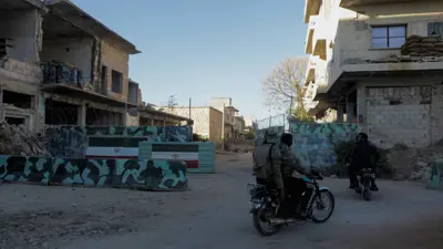 مقاتلون الفصائل المسلحة أمام موقع عسكري مهجور في كفرنبل، سوريا