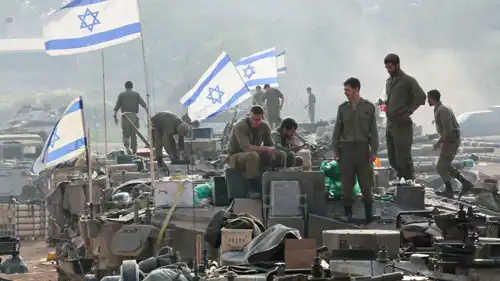  جنود إسرائيليون يقفون على دبابات قرب حدود غزة