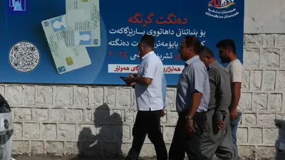 مواطنون يمرون أمام لوحة للتصويت في انتخابات كردستان العراق