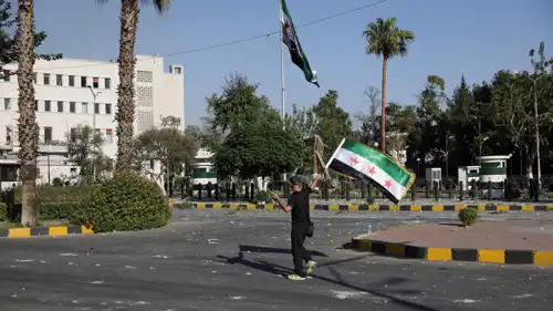 سوري يحمل علم بلاده بعد غارات إسرائيلية على دمشق