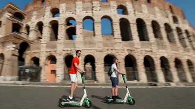 سائحان يركبان سكوتر أمام الكولوسيوم في روما