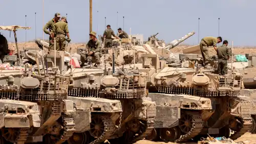  جنود إسرائيليون يقفون فوق دبابات على حدود غزة 