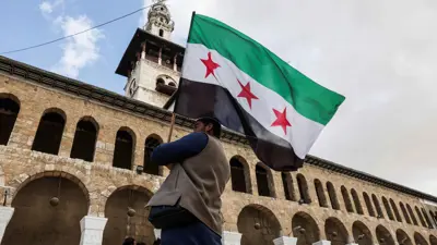 سوري يرفع العلم الجديد