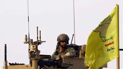 جندي أمريكي إلى جانب علم "قسد"