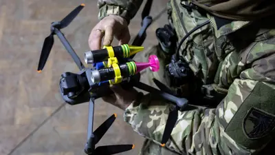 جندي أوكراني يعلق قنابل على طائرة مسيّرة صغيرة