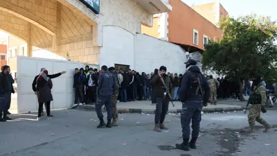 مسلحون سوريون يقفون قرب طابور من المدنيين